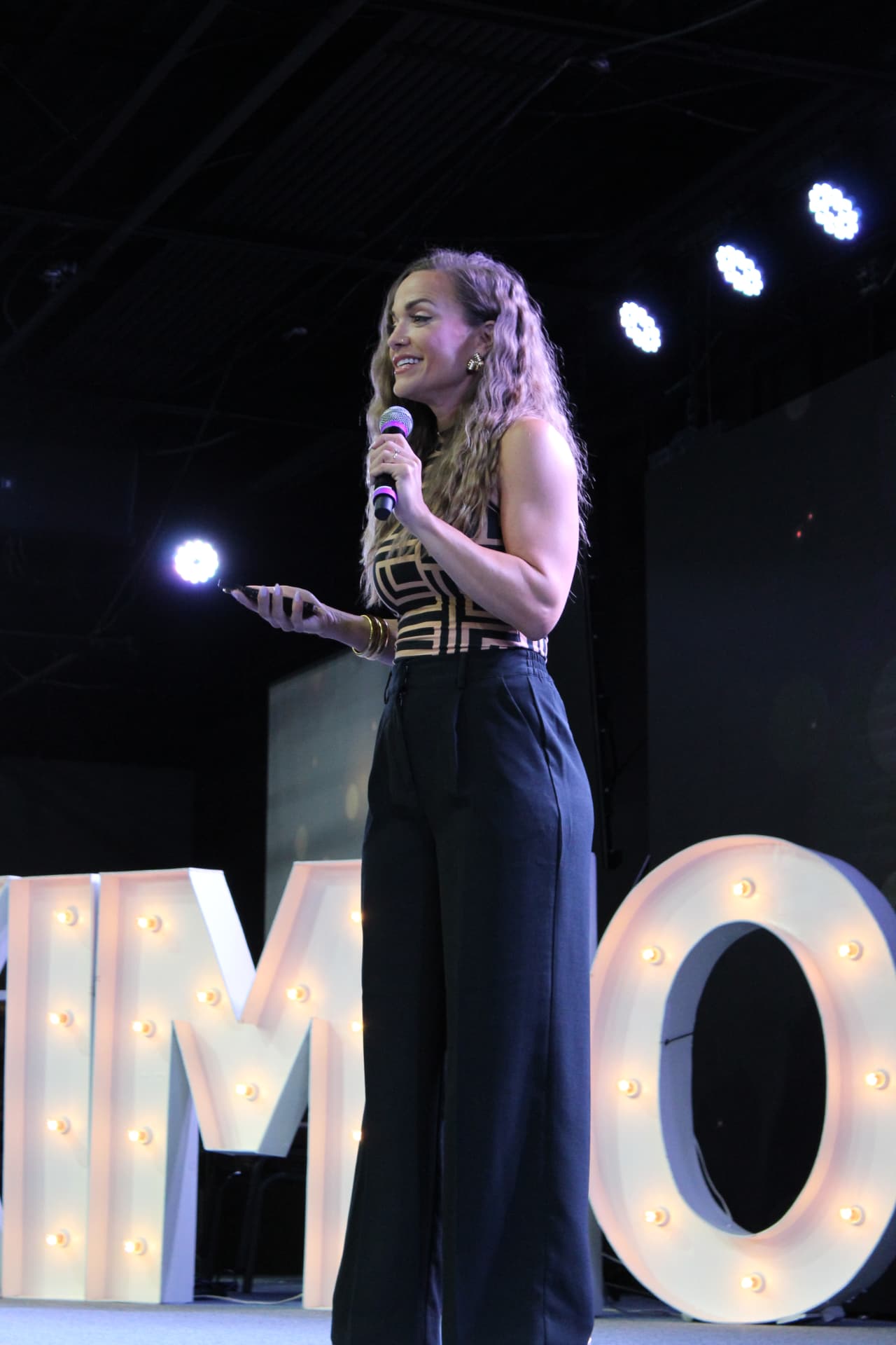 Molly Gomez speaking on stage to an audience of women.